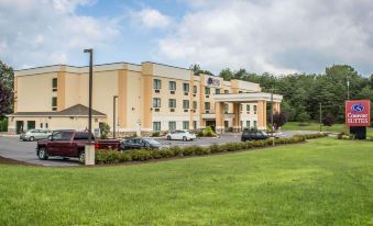 a large hotel with a parking lot in front of it and trees in the background at Comfort Suites Lewisburg