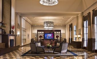 a spacious lobby with high ceilings , multiple couches , chairs , and a television mounted on the wall at New Haven Hotel