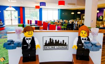 two lego figures dressed as a man and a woman are standing in front of a skyline lounge at Legoland® Florida Resort