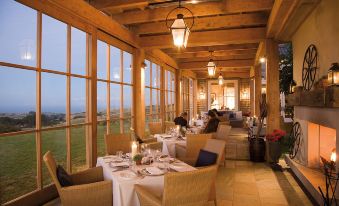 a dining room with wooden tables and chairs arranged for a large group of people to enjoy a meal at Rosewood Cape Kidnappers