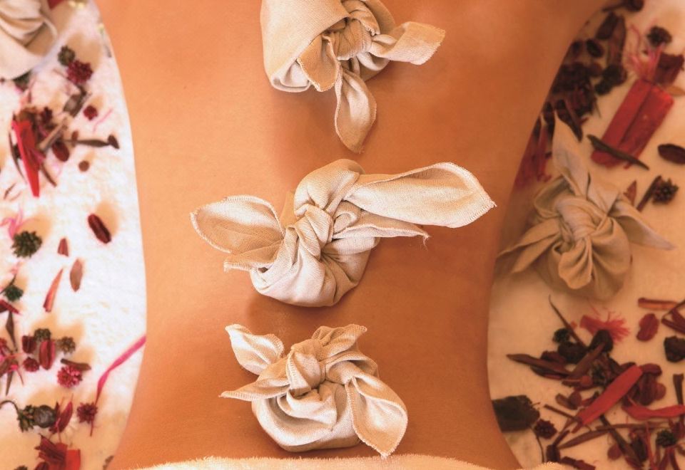 a woman lying on a massage table with white towels placed on her back at Grand Hotel Baia Verde