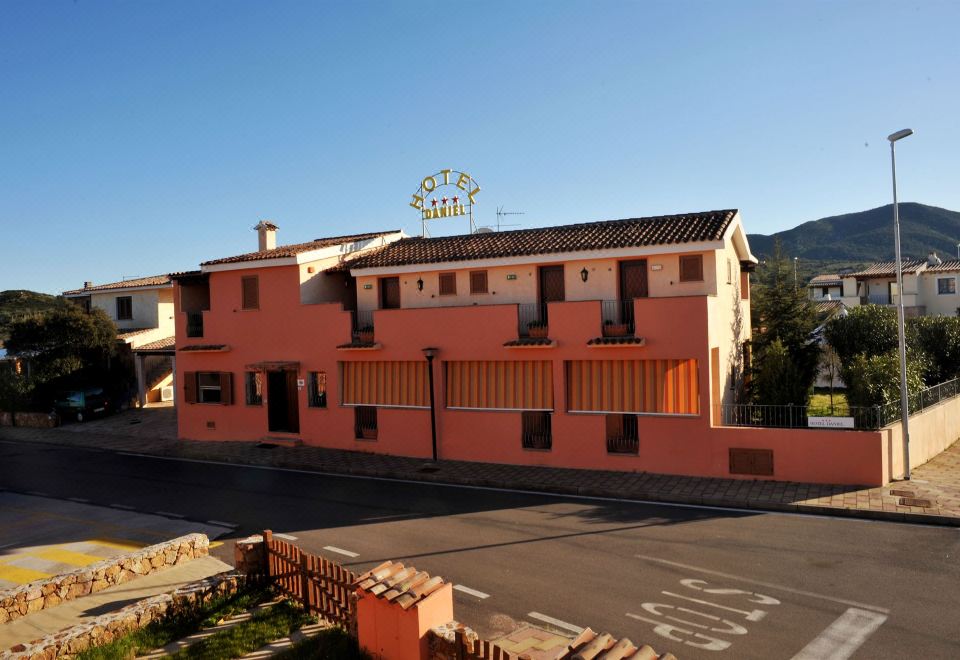 "a pink building with a sign that reads "" hotel "" is situated on a street corner" at Hotel Daniel