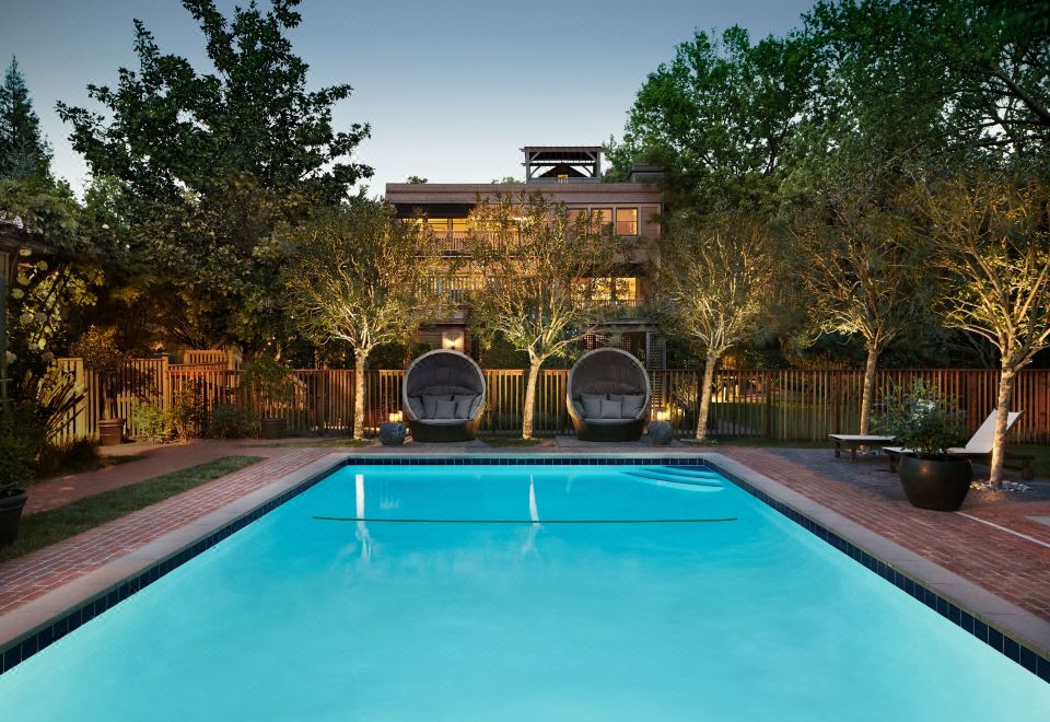 a large swimming pool is surrounded by trees and a building with two lounge chairs at Gaige House