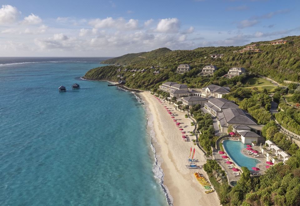 aerial view of a sandy beach surrounded by tall buildings , with a body of water in the background at Mandarin Oriental, Canouan