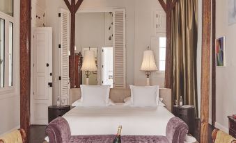 a bedroom with a large bed , purple and white bedding , wooden beams , and chairs around a coffee table at Hotel B