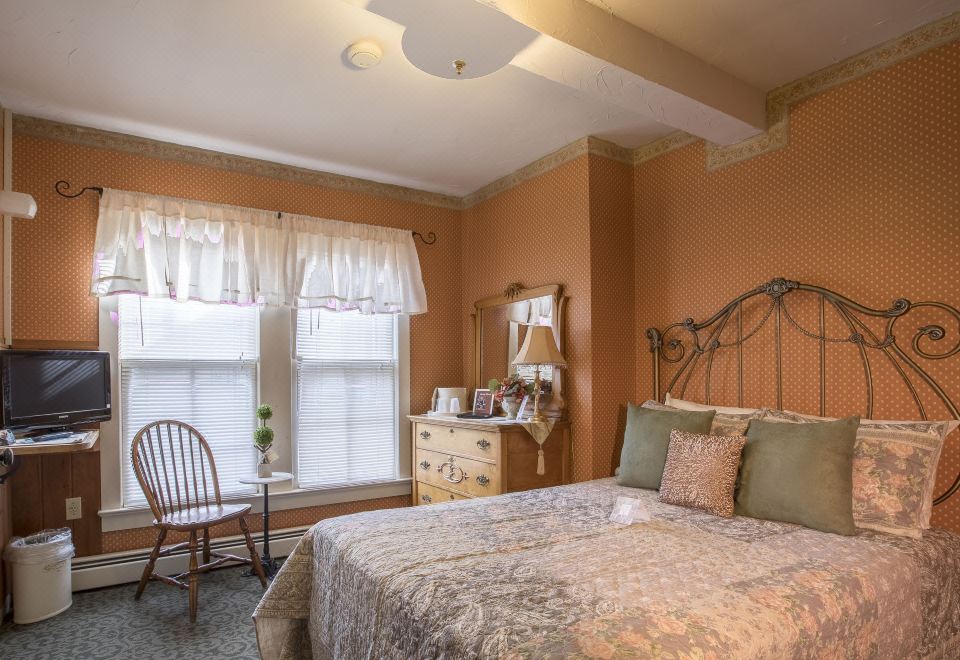 a cozy bedroom with a large bed , a dresser , and a mirror on the wall at Stroudsmoor Country Inn