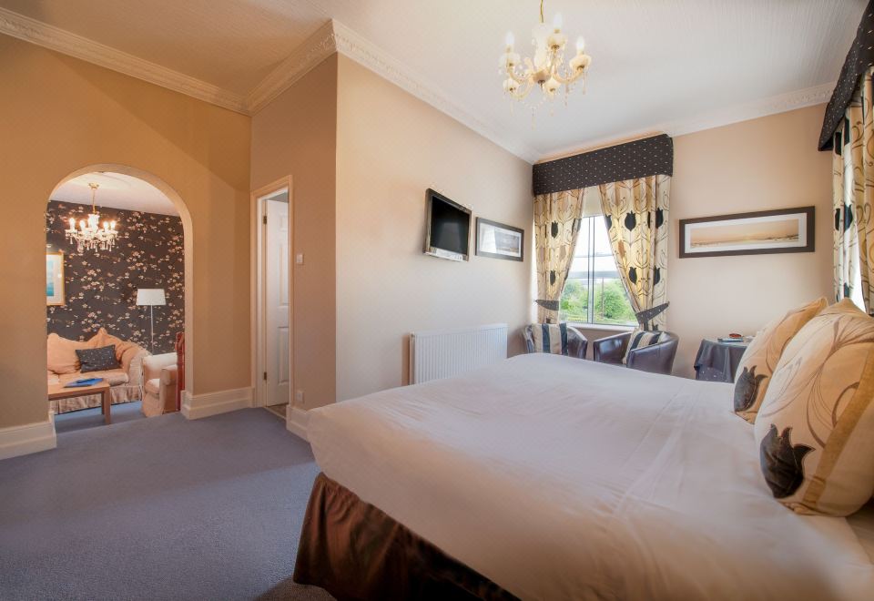 a large bedroom with a king - sized bed , multiple chairs , and a tv mounted on the wall at Best Western New Holmwood Hotel