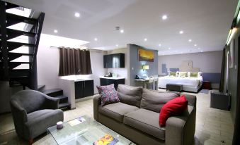 a modern living room with a gray couch , glass coffee table , and multiple seating areas at Travelodge Kasane