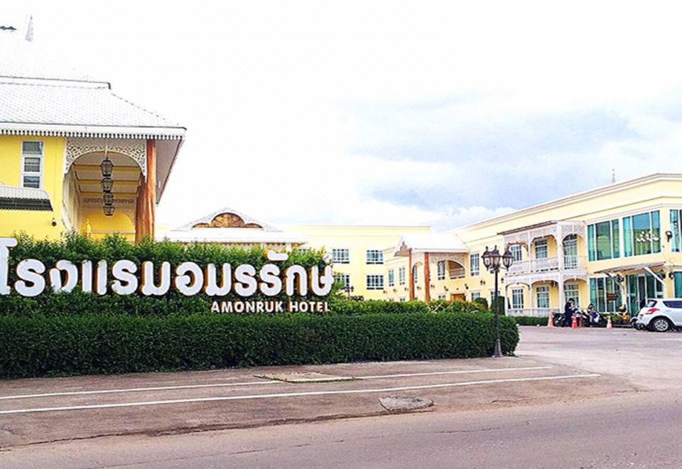 "a large hotel building with a sign that reads "" süeusnung "" on the front , surrounded by bushes and trees" at Amonruk  Hotel 2