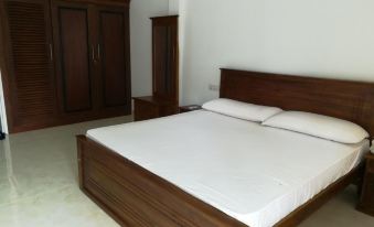 a large , empty bedroom with a wooden bed and matching dresser , set against a white wall at Sea Breeze