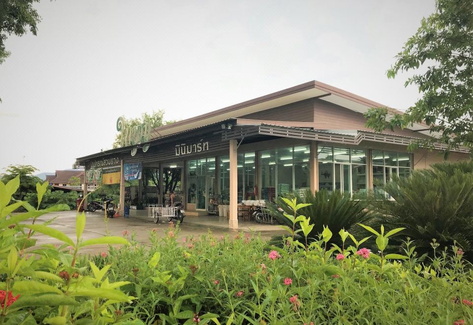 a modern building with a green roof and large windows , surrounded by lush greenery and flowers at Baiboon Resort