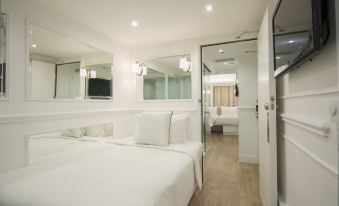 The bedroom is empty and white, with two beds and a large mirror in the middle at Mini Hotel Causeway Bay