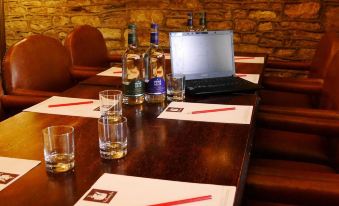 a wooden dining table with two glasses , a laptop on the table , and bottles of alcohol at The Snooty Fox