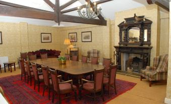 a dining room with a large wooden table surrounded by chairs , a fireplace , and a fireplace mantle at Londonderry Arms Hotel
