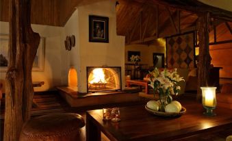 a cozy living room with a fireplace , a dining table , and various items on the table at Elewana Lewa Safari Camp