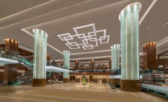 a large , modern hotel lobby with multiple columns and a chandelier hanging from the ceiling at Grand Hyatt Manila