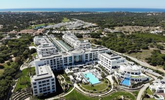 a bird 's eye view of a large resort with multiple buildings , a pool , and a golf course at Conrad Algarve