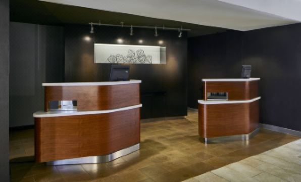 a hotel lobby with two wooden reception desks , one on the left and the other on the right at Sonesta Select Raleigh Durham Airport Morrisville