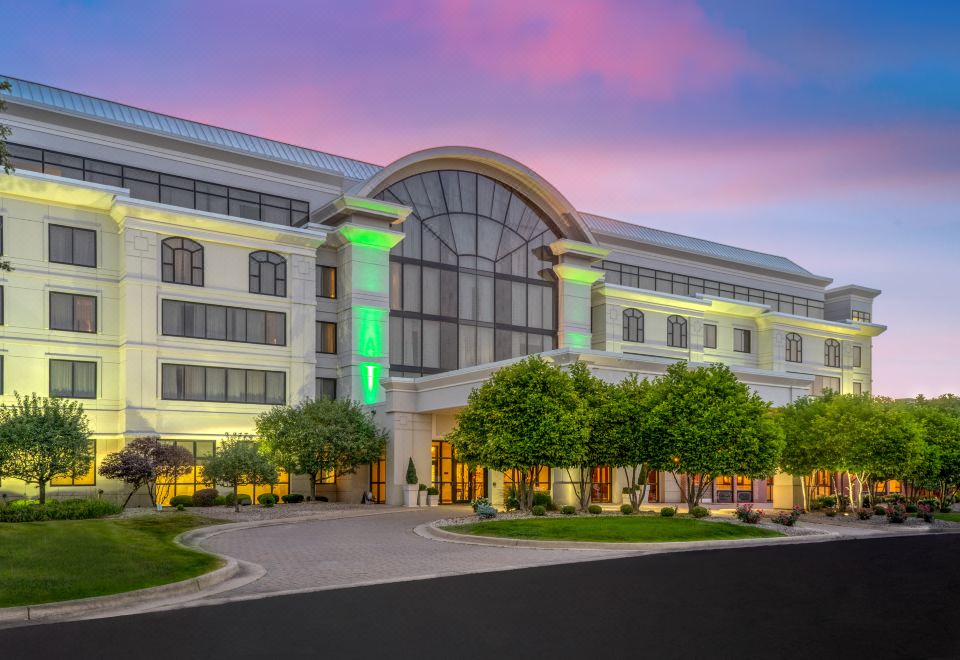 a large hotel with a green light on the front entrance , surrounded by trees and a parking lot at Holiday Inn Wilmington