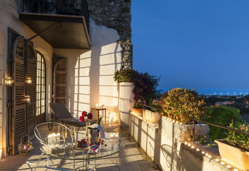 a patio with a table and chairs , surrounded by potted plants and overlooking the ocean at Chateau le Cagnard