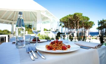 a dining table set with a white tablecloth , wine glasses , forks , knives , and plates , ready for a meal at La Coluccia