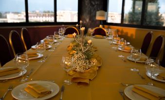 a dining table set with multiple plates , cups , and wine glasses , along with a centerpiece of flowers at Park Hotel
