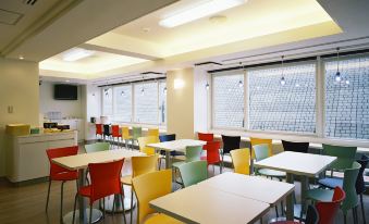 a brightly lit room with multiple tables and chairs arranged in rows , creating a classroom setting at Chisun Inn Munakata