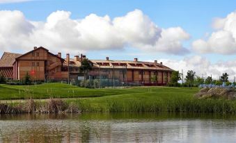 a large building with a red roof is situated next to a body of water at Exe Layos Golf