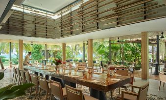 a large dining room with long wooden tables and chairs arranged for a group of people to enjoy a meal at PARKROYAL Penang Resort