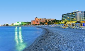 a beach with clear blue water and a large building in the background at night at Mediterranean Hotel