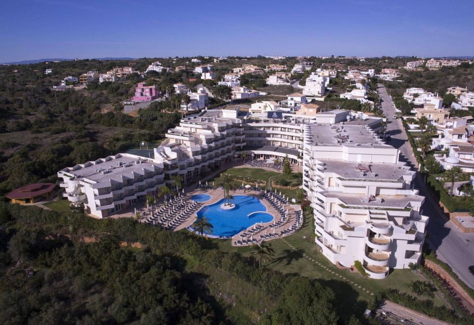 aerial view of a large white hotel complex with multiple buildings , pools , and trees in the background at Vila Gale Nautico