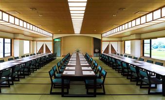 a large , empty conference room with multiple rows of chairs and tables , all set up for meetings at Yufuin Hotel Shuhokan