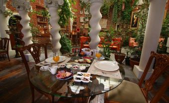 a dining table set with a variety of food items and utensils , including bowls , forks , knives , spoons , and cups at Sacred House