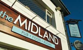 "a building with a sign that reads "" the midland pub "" and a blue sky in the background" at The Midland Hotel
