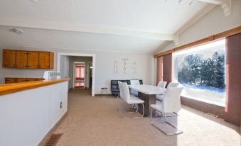 a dining room with a long wooden dining table and chairs , along with a kitchen area at White House Farm