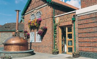 a brick building with a large copper vat in front of it , surrounded by potted plants at Angel Hotel