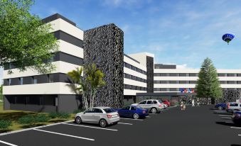 a modern building with a black and white facade , surrounded by cars parked in a parking lot at Everness Hotel & Resort