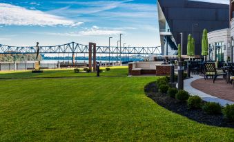 a grassy area with a bridge in the background , and a building in the foreground at Holiday Inn Owensboro Riverfront