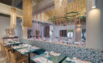 a modern restaurant with multiple dining tables and chairs , as well as a chandelier hanging from the ceiling at Emotions by Hodelpa - Juan Dolio