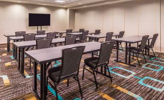 a conference room with several rows of tables and chairs , a television on the wall , and carpeted flooring at Residence Inn St. Louis Westport