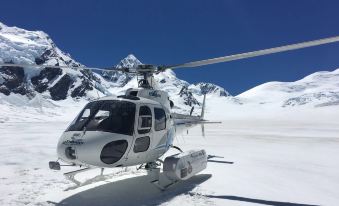 a white helicopter is parked on a snowy mountain with a blue sky in the background at Sunset Motel