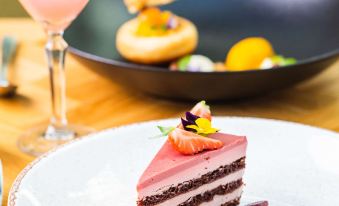 a white plate with a slice of cake on it , accompanied by a pink cocktail and other food items at Hyatt Regency Birmingham