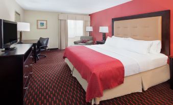a large bed with a red blanket is in the center of a room with red walls at Wyndham Garden Dover