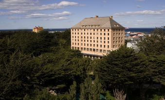 a large hotel building surrounded by trees , with a view of the ocean in the background at Hotel Cabo de Hornos