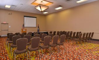 a conference room with rows of chairs arranged in front of a projector screen , ready for a meeting or presentation at Ramada Plaza by Wyndham Sheridan Hotel & Convention Center