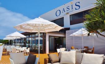an outdoor patio with white umbrellas , lounge chairs , and tables under a clear blue sky at Okuma Private Beach & Resort
