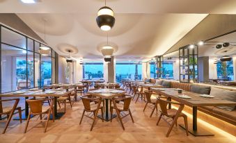 a large dining room with wooden tables and chairs , along with a view of the ocean at Cascade Wellness Resort