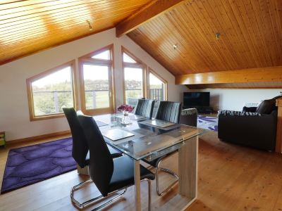 a large , open room with a wooden ceiling and a glass dining table surrounded by chairs at Moon Face