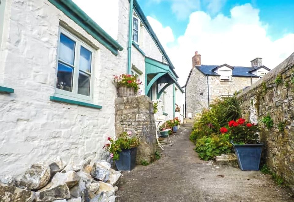 a quaint village street with white and green houses , surrounded by stone walls and potted plants at Garden View