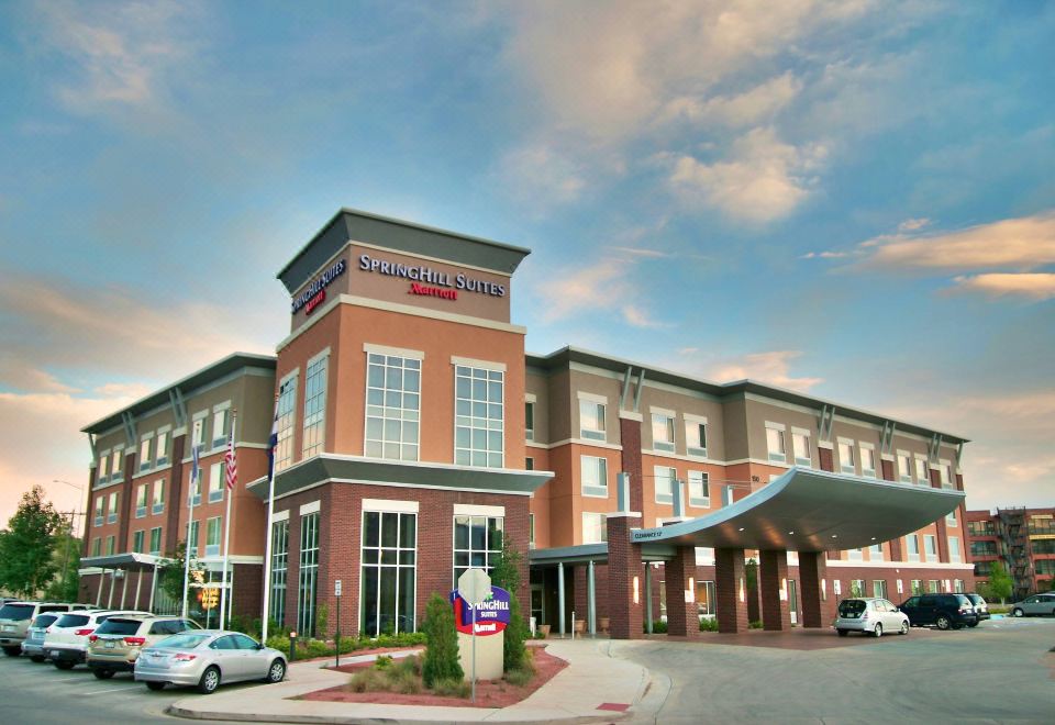 a modern hotel building with a red brick facade and large windows , located in a city setting at SpringHill Suites Pueblo Downtown